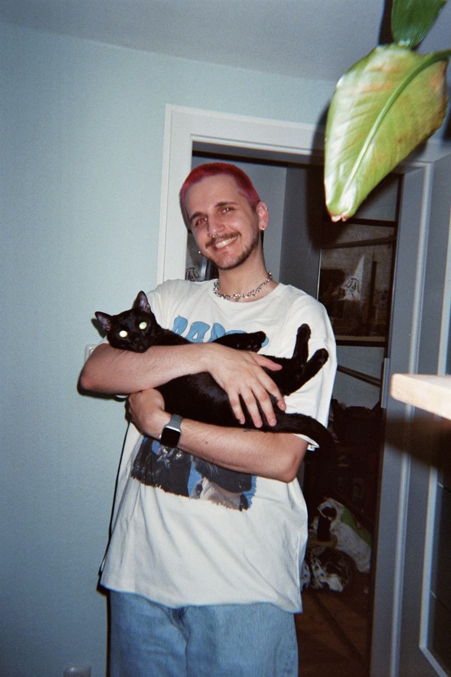 Me smiling and holding my black cat Barty in my arms at home