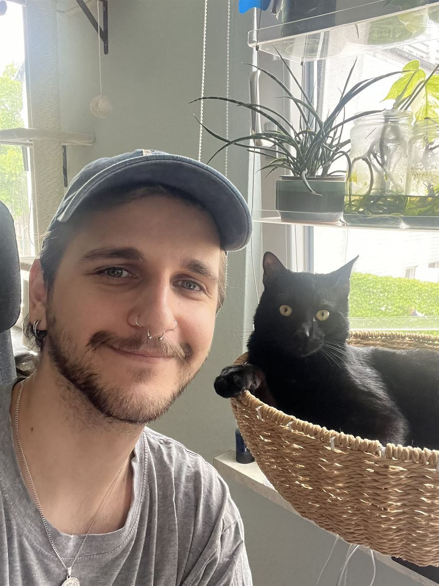 Selfie of me next to my black cat Barty, who is lying in a basket by the window