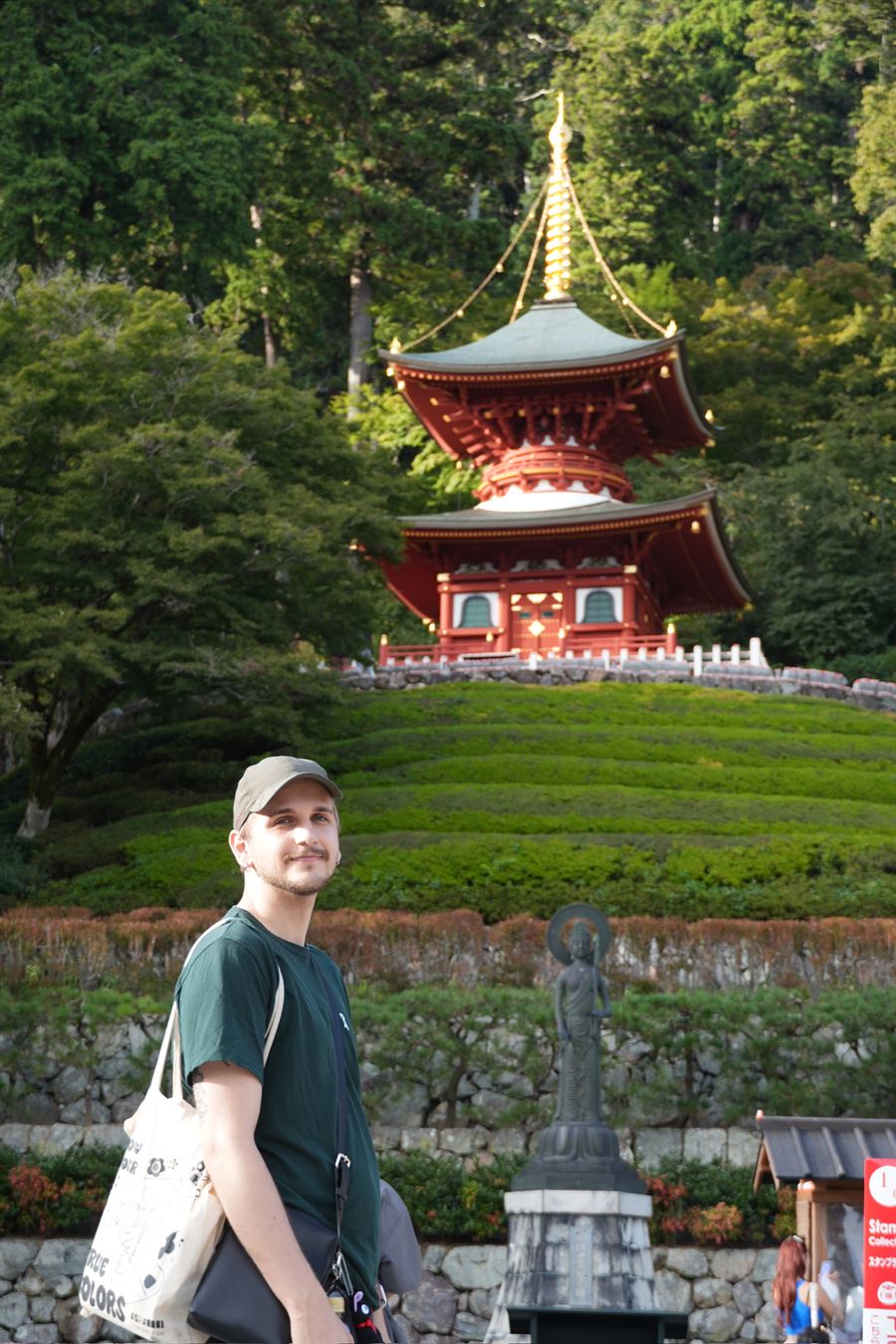 Me in front of a red pagoda on a green hillside in Japan